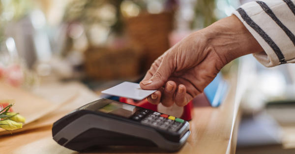 An older woman uses a contactless card on a payment terminal. 