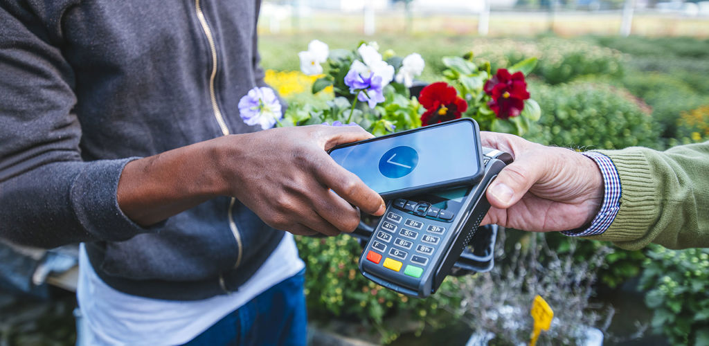 A payment being made in a garden center, using a phone and a payment terminal